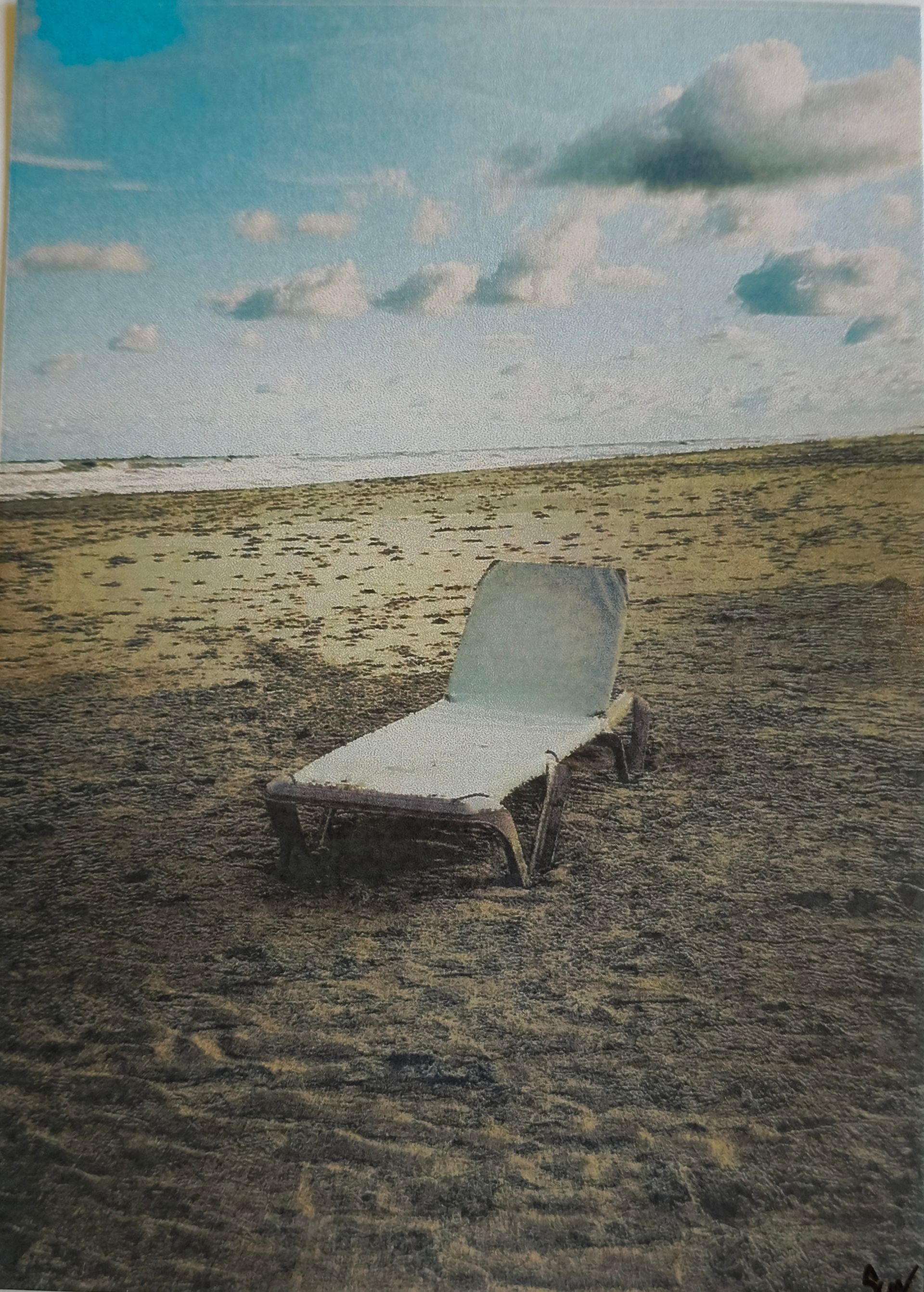 Postkaart van een eenzame ligstoel staat op een zanderig strand onder een bewolkte blauwe hemel.