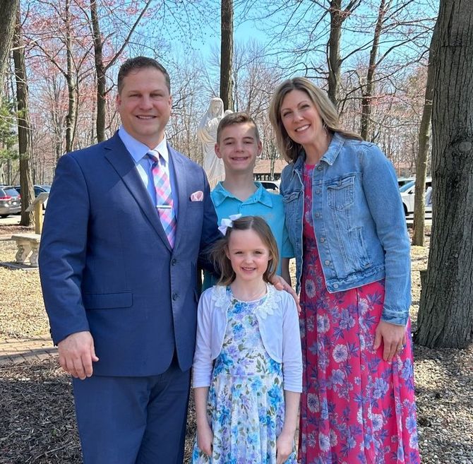 Family of four posing outdoors in spring, wearing formal and casual clothes.