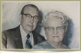 Portrait of an older couple in formal attire, standing close together against a soft painted background.