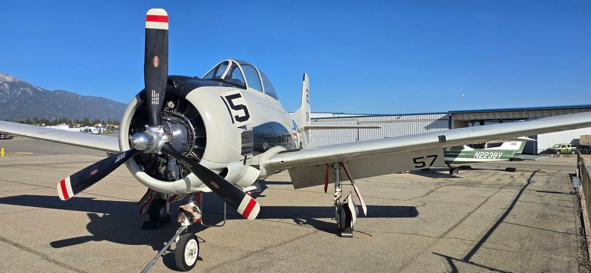 Vintage propeller aircraft parked on a tarmac under a clear blue sky