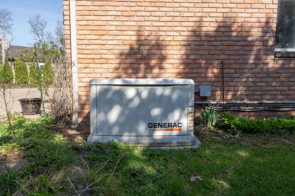 Generac outdoor generator beside a brick house in a grassy yard, partly shaded by trees
