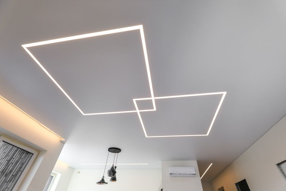 Modern ceiling with two overlapping geometric LED light fixtures in a bright room
