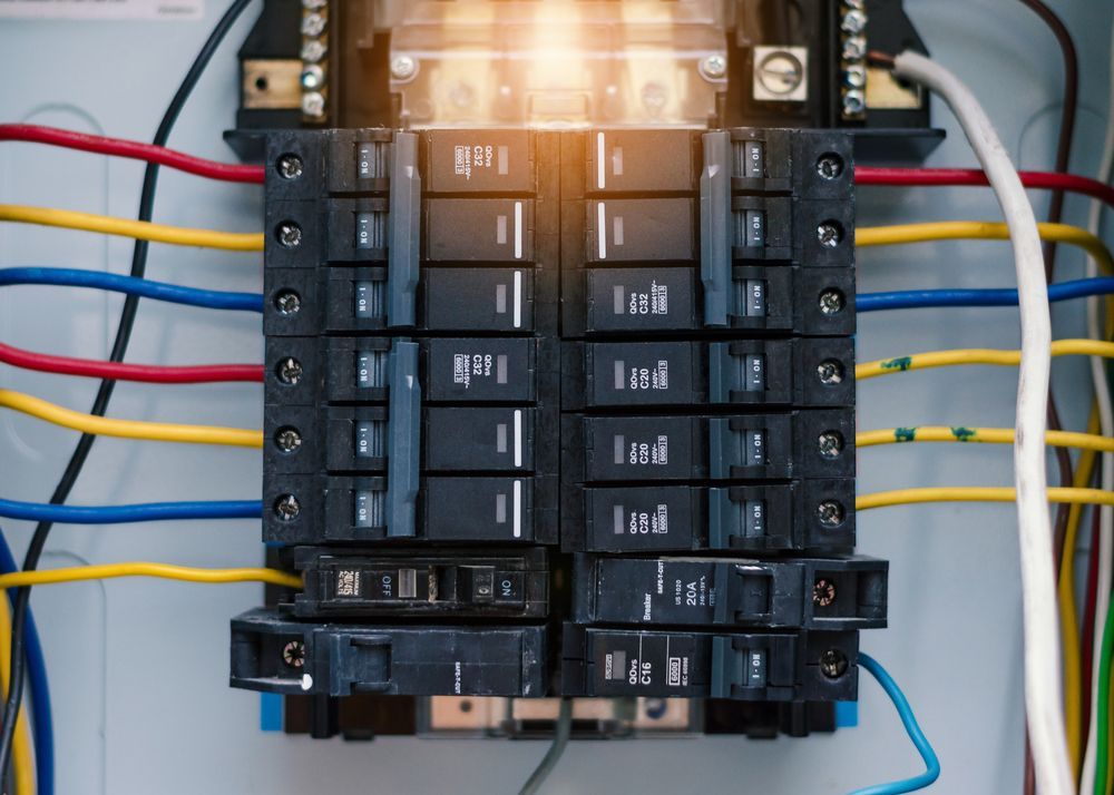 Electrical breaker panel with rows of black switches and colored wires connected on both sides