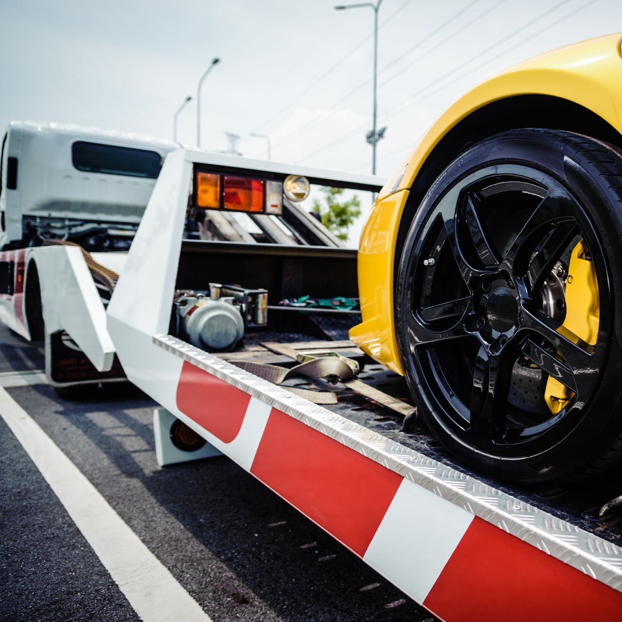 A yellow sports car is being towed by a tow truck.