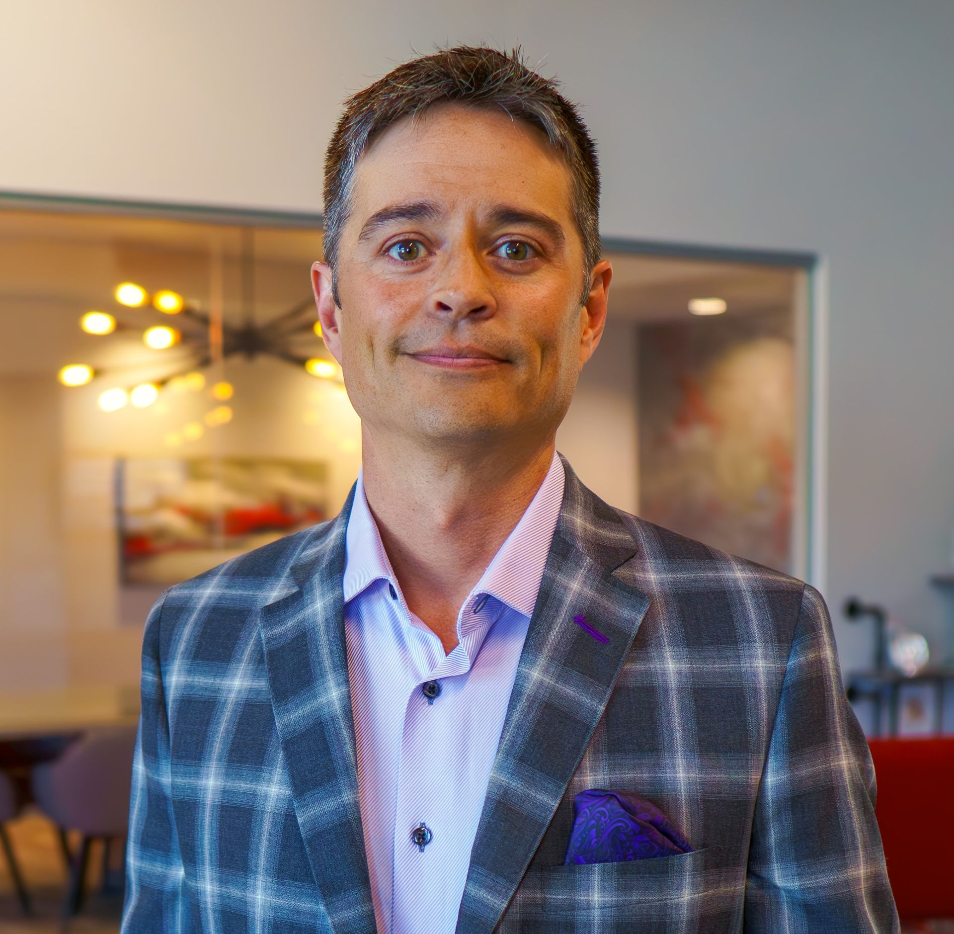 A man is wearing a plaid jacket and a purple pocket square.