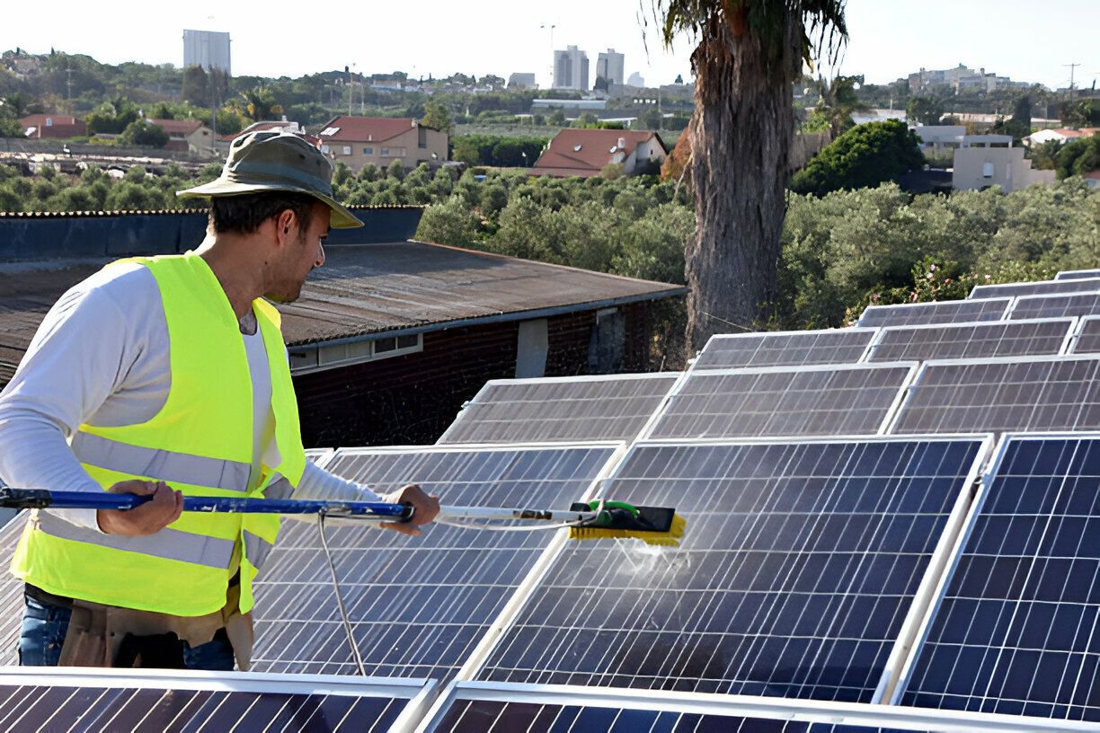 A man is cleaning solar panels with a brush
