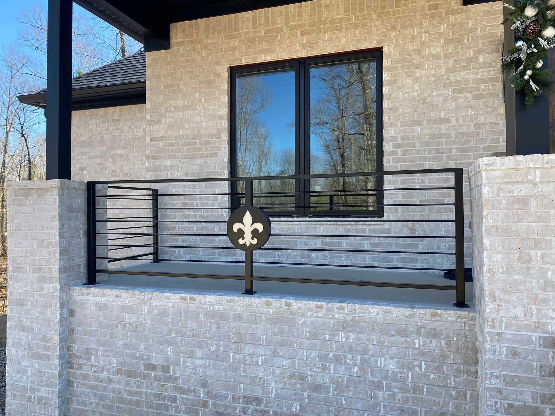 Modern brick house patio with black metal railing and large window on a raised porch