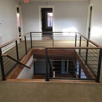 Interior with staircase and modern black railings leading down.
