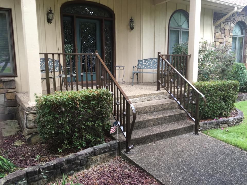 Brown metal handrails and steps leading up to a house porch with a blue door.