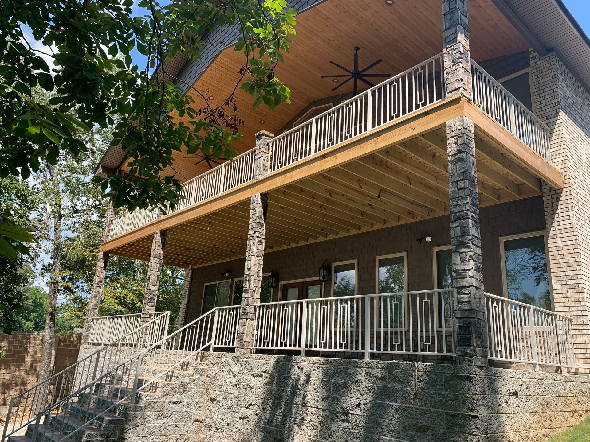Stone cabin with wooden balcony and porch. Exterior view with trees in background.