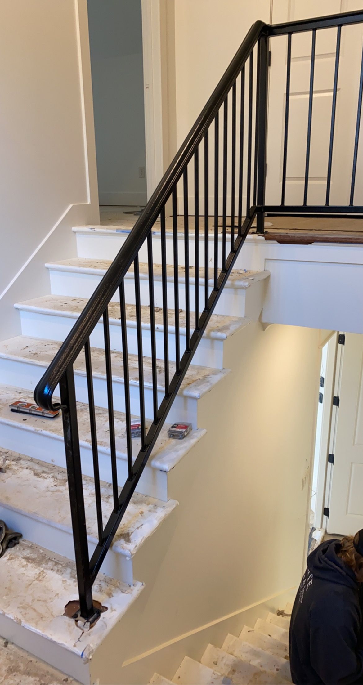 Black metal handrail on white staircase.