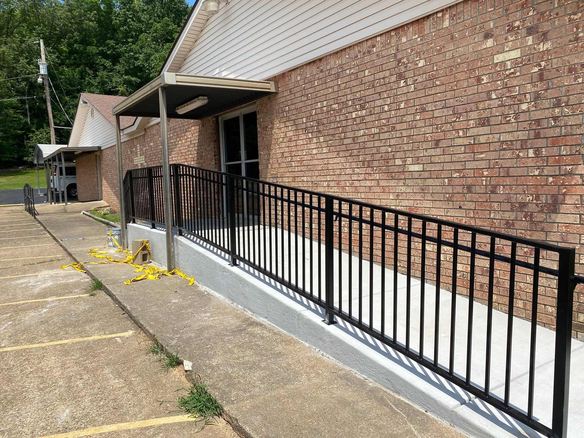Brick building entrance with black metal ramp railing and concrete walkway