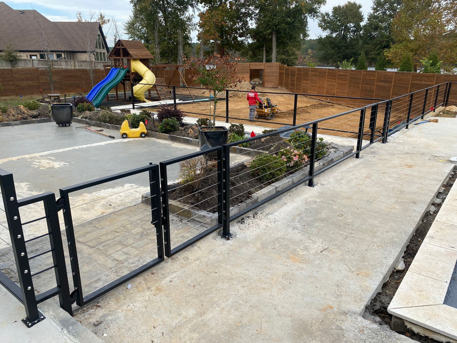 Small playground with slide, fenced play area, and a paved path beside it