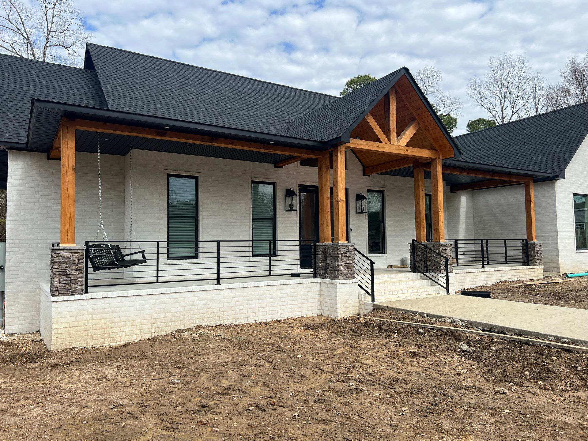 Modern single-story house with white brick, dark roof, and wood-accented front porch