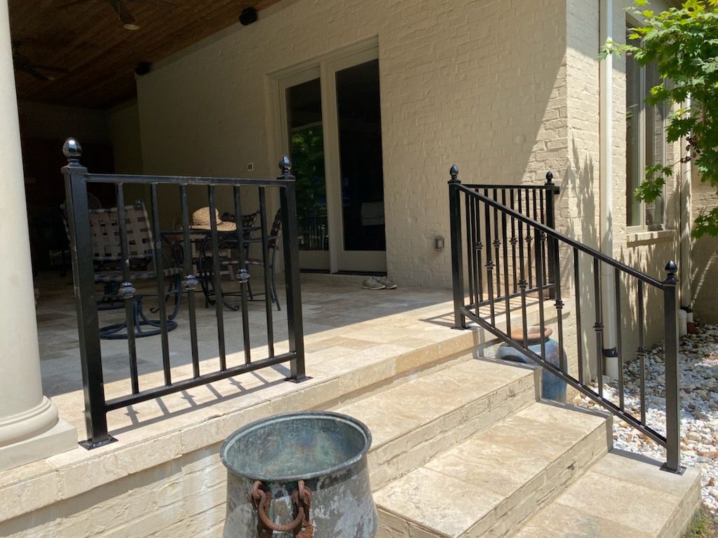 Patio steps with black railings leading to a covered porch and glass doors