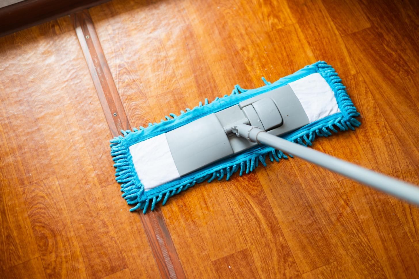 Blue mop cleaning a wooden floor