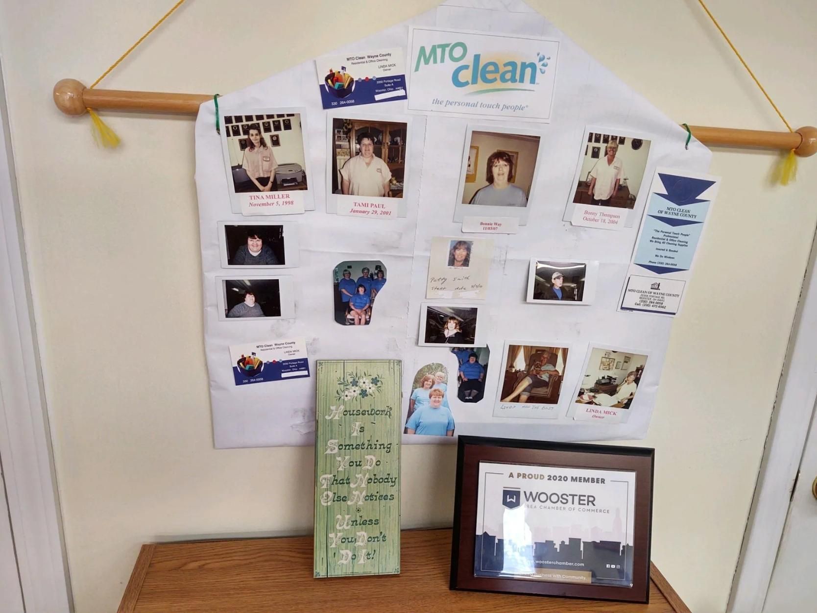 Bulletin board with photos and notes above a wooden shelf holding a framed award and a green card.