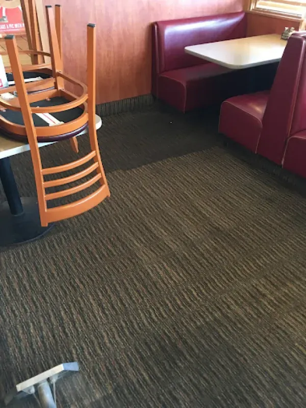 A restaurant with tables and chairs and a vacuum cleaner on the floor