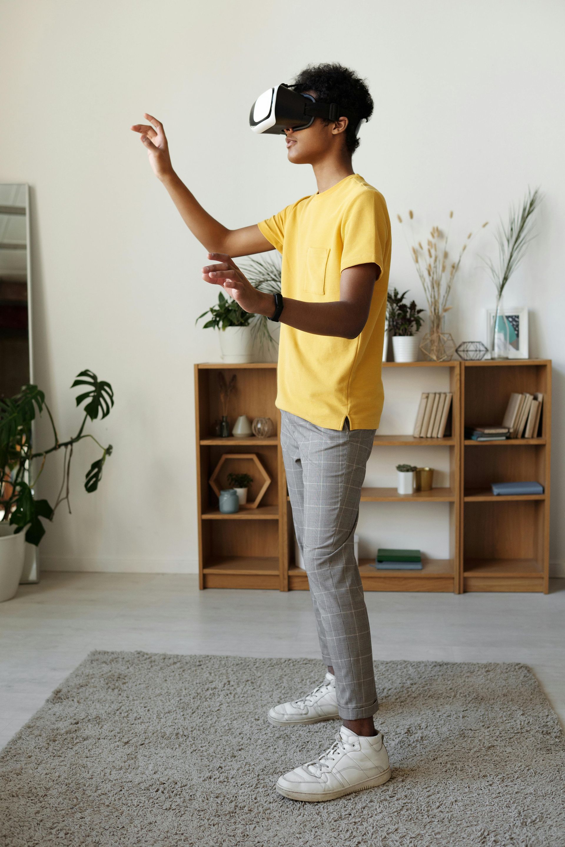 A young man is wearing a virtual reality headset in a living room.