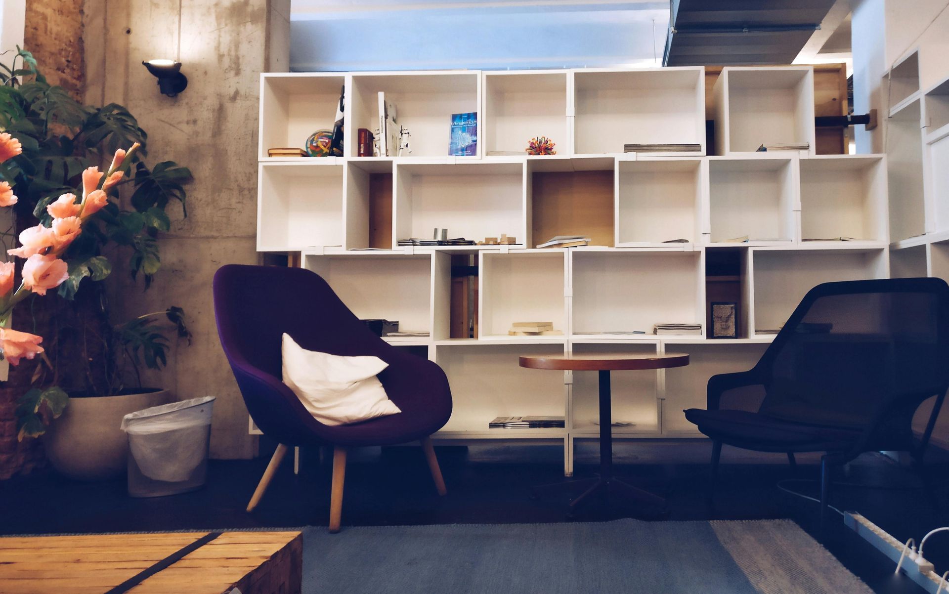 A living room with a purple chair and a table in front of a bookshelf.