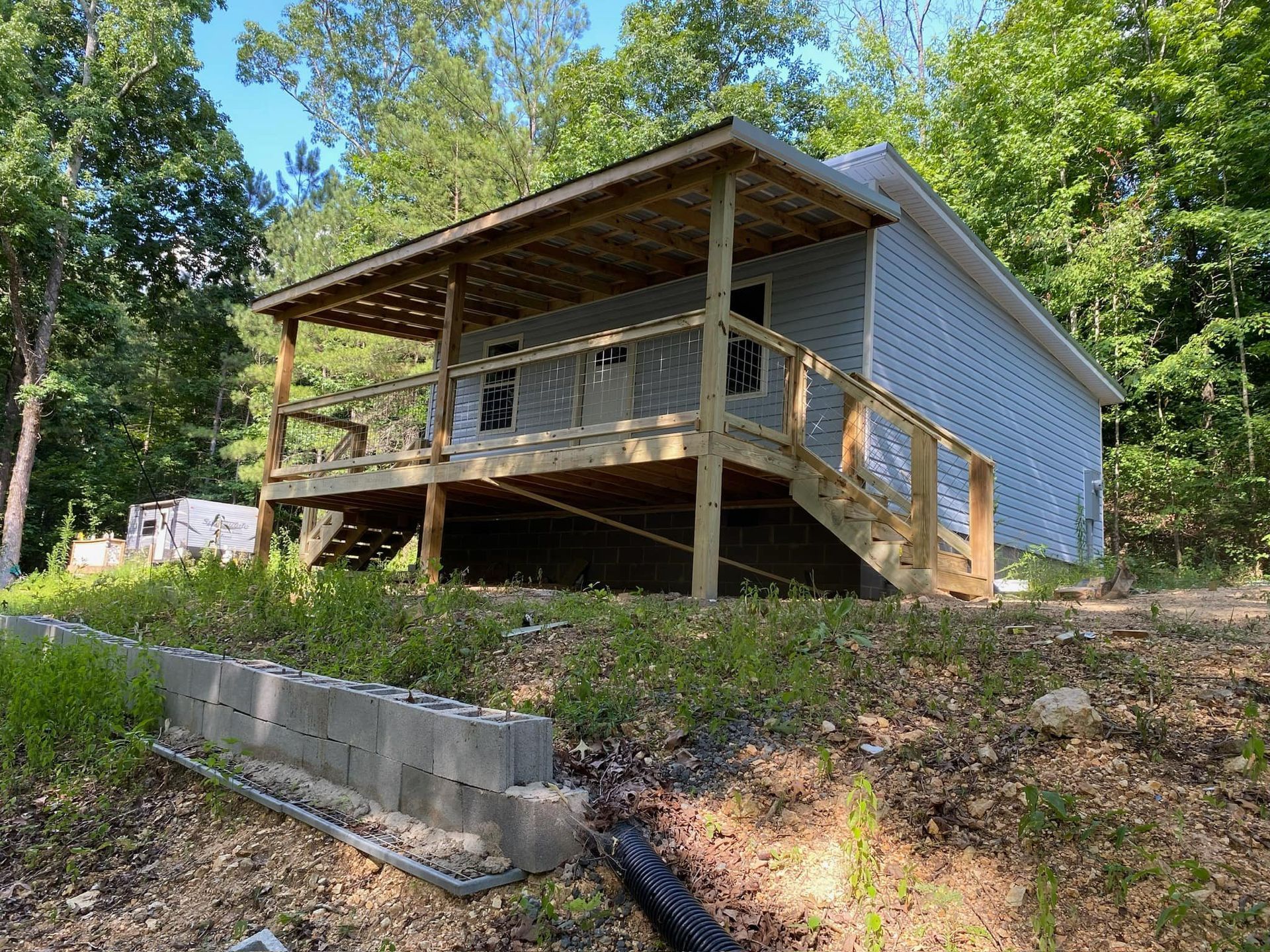 A small white house with a wooden deck in the woods.