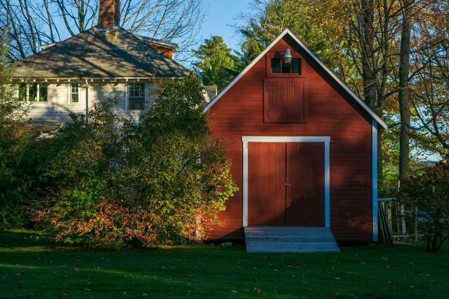 A red barn is in front of a white house