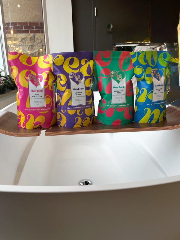 Four colorful packaged bath products displayed around a white bathtub.