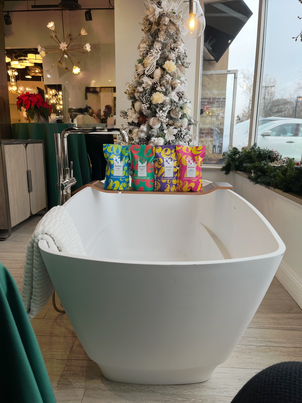 Modern white bathtub in a decorated showroom beside a Christmas tree and colorful gift bags