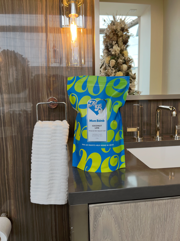Blue and green patterned gift bag on a bathroom counter beside a white towel holder and sink