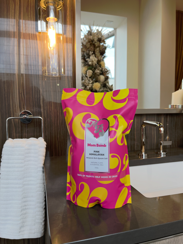 Pink and yellow patterned gift bag on a counter in a modern bathroom or vanity area