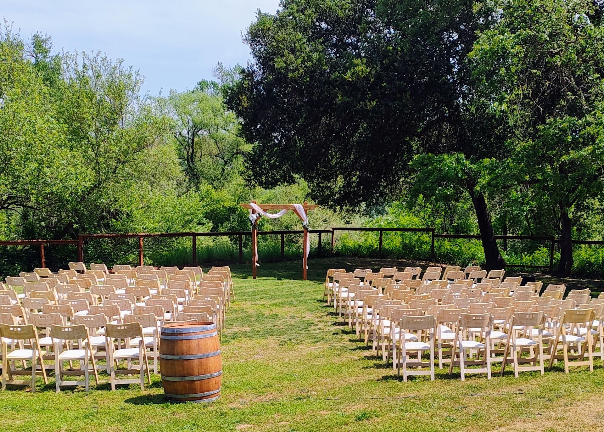 Chairs set on the lawn facing a wedding alter with a wooden archway