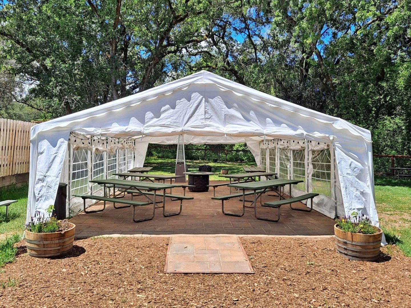 large canvas pavillion on grass with large trees surrounding it