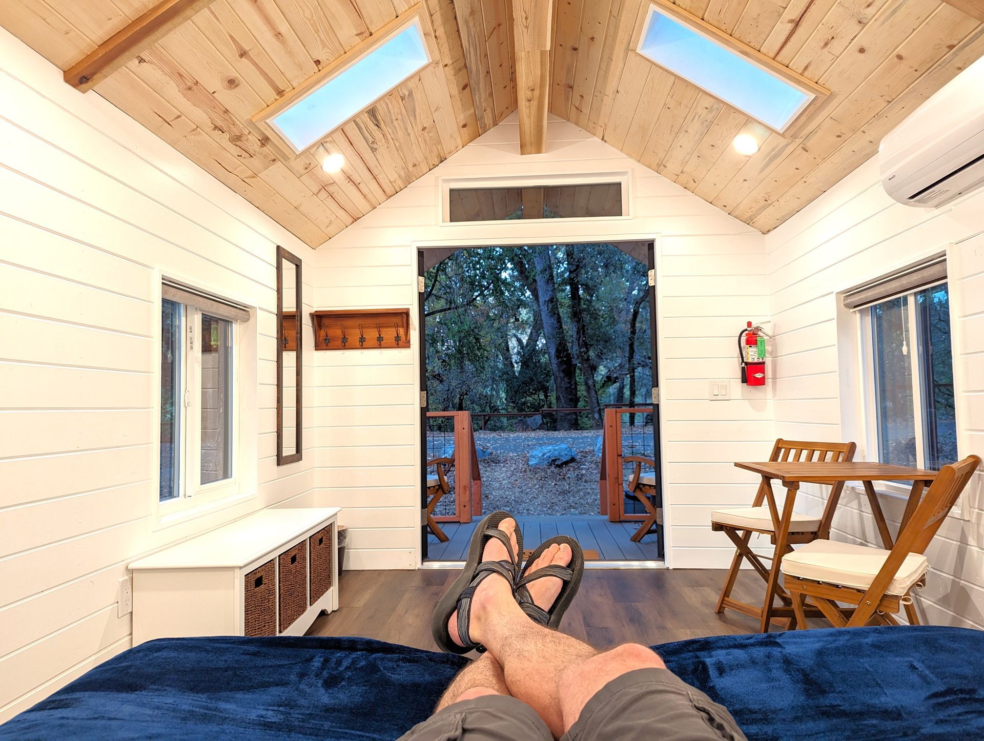 A person is laying on a bed in a small house with their feet up.