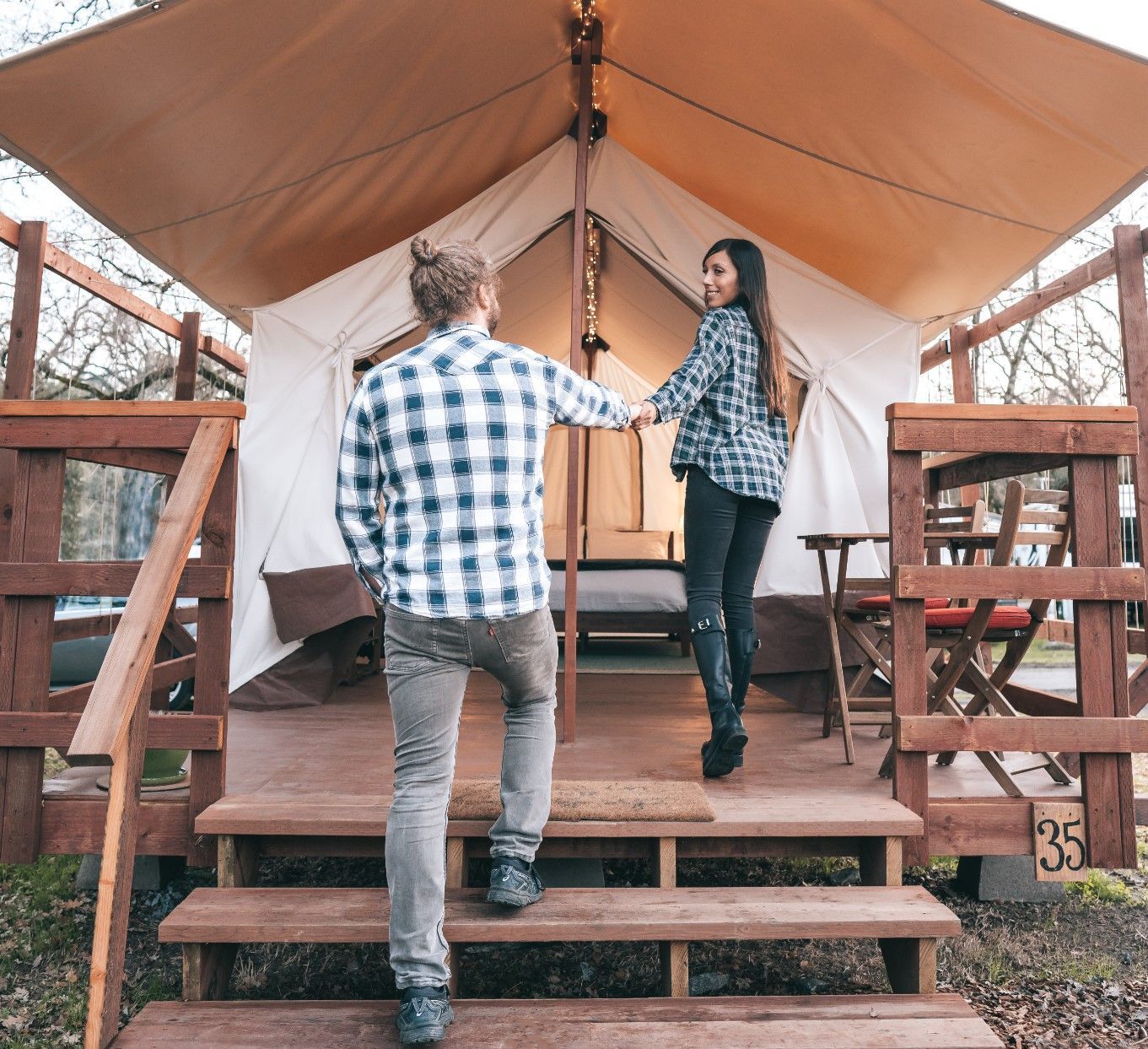 A man and a woman are standing outside of a tent.