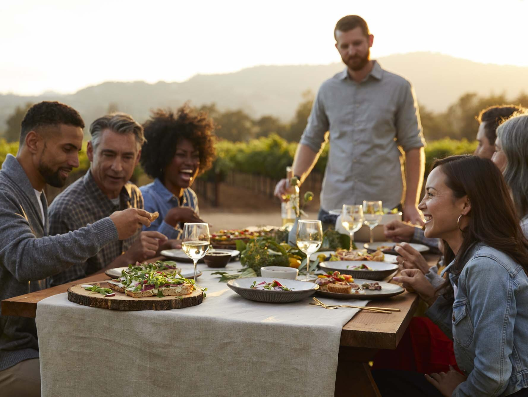 A group of people are sitting at a table eating food and drinking wine.
