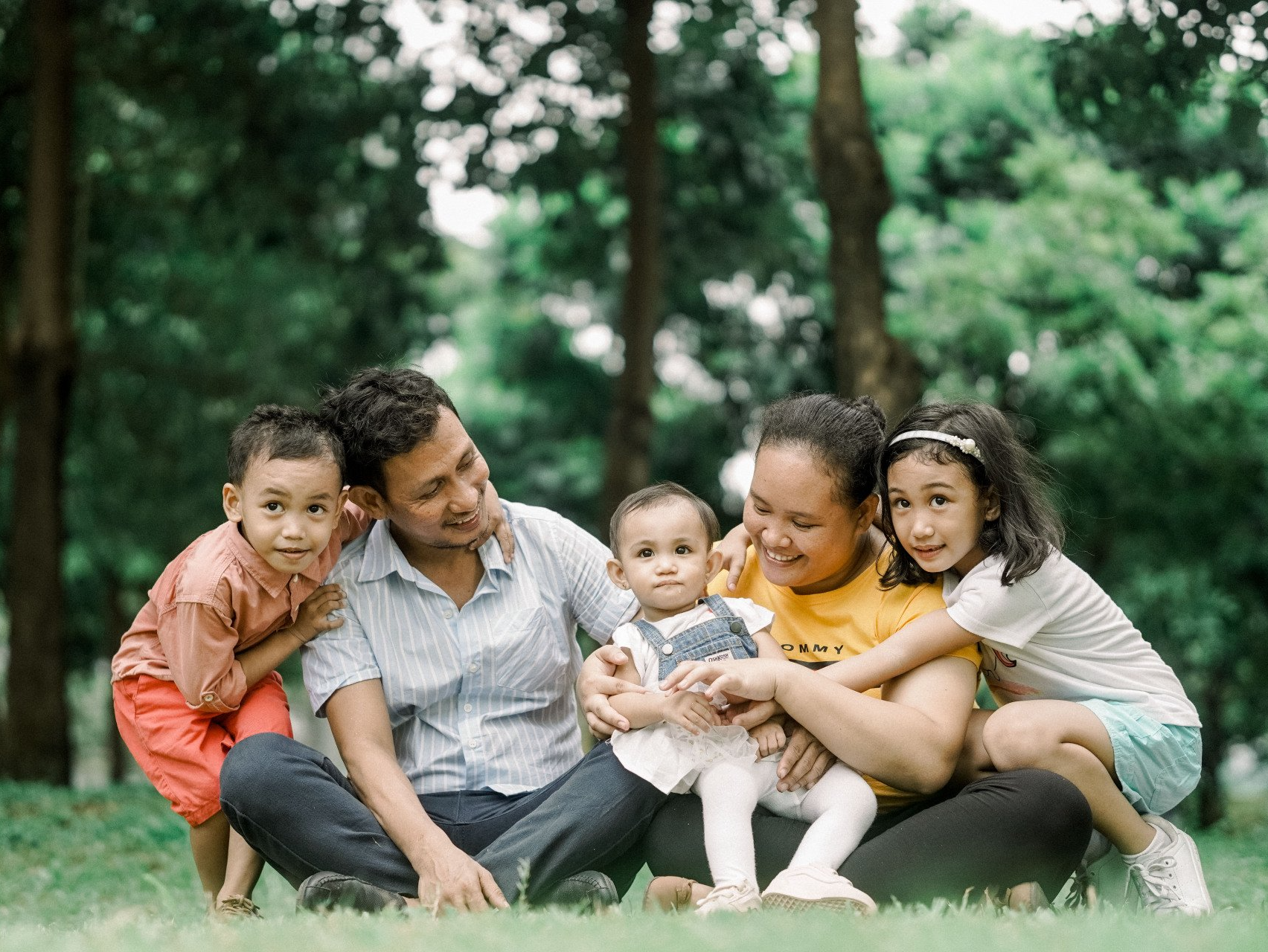 A family is sitting on the grass in a park.