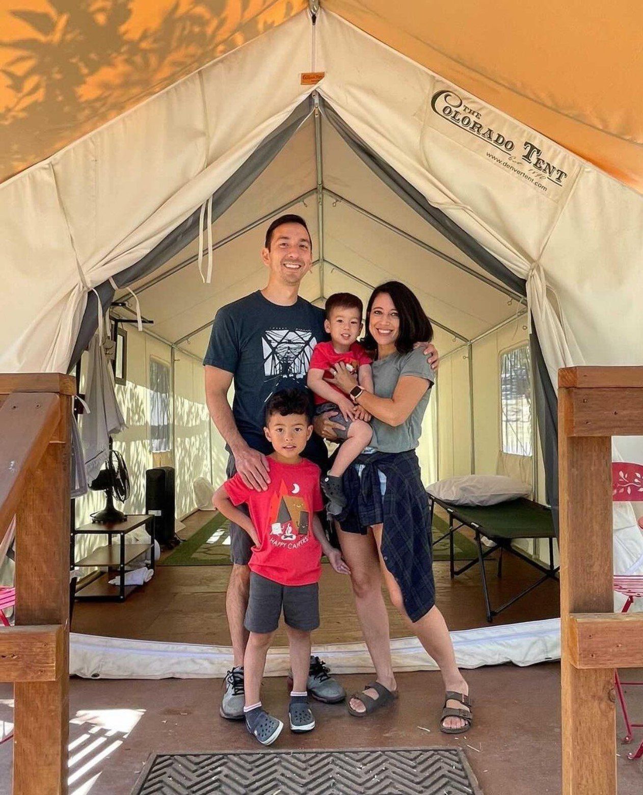 A family is posing for a picture in front of a tent.