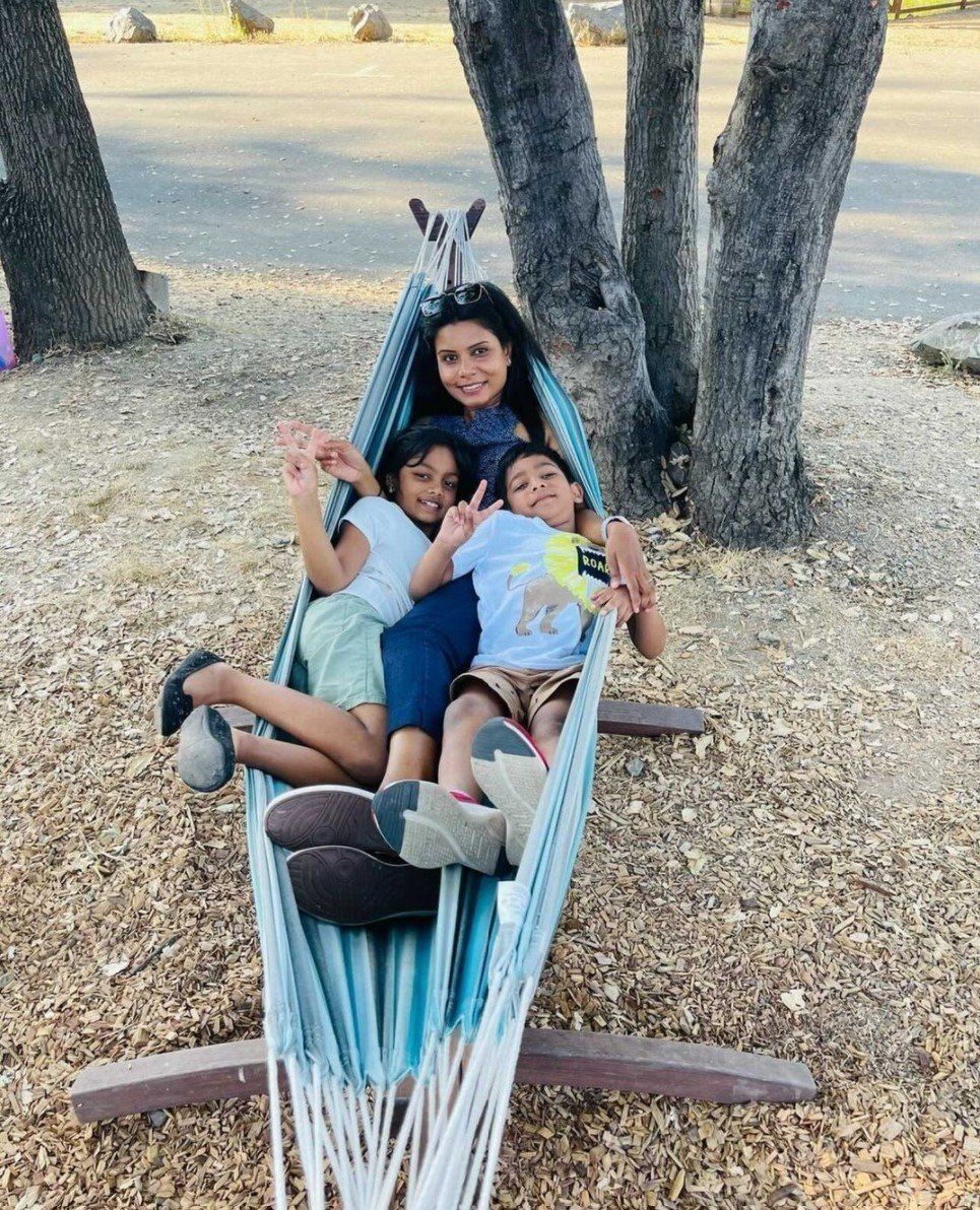 A woman and two children are sitting in a hammock.