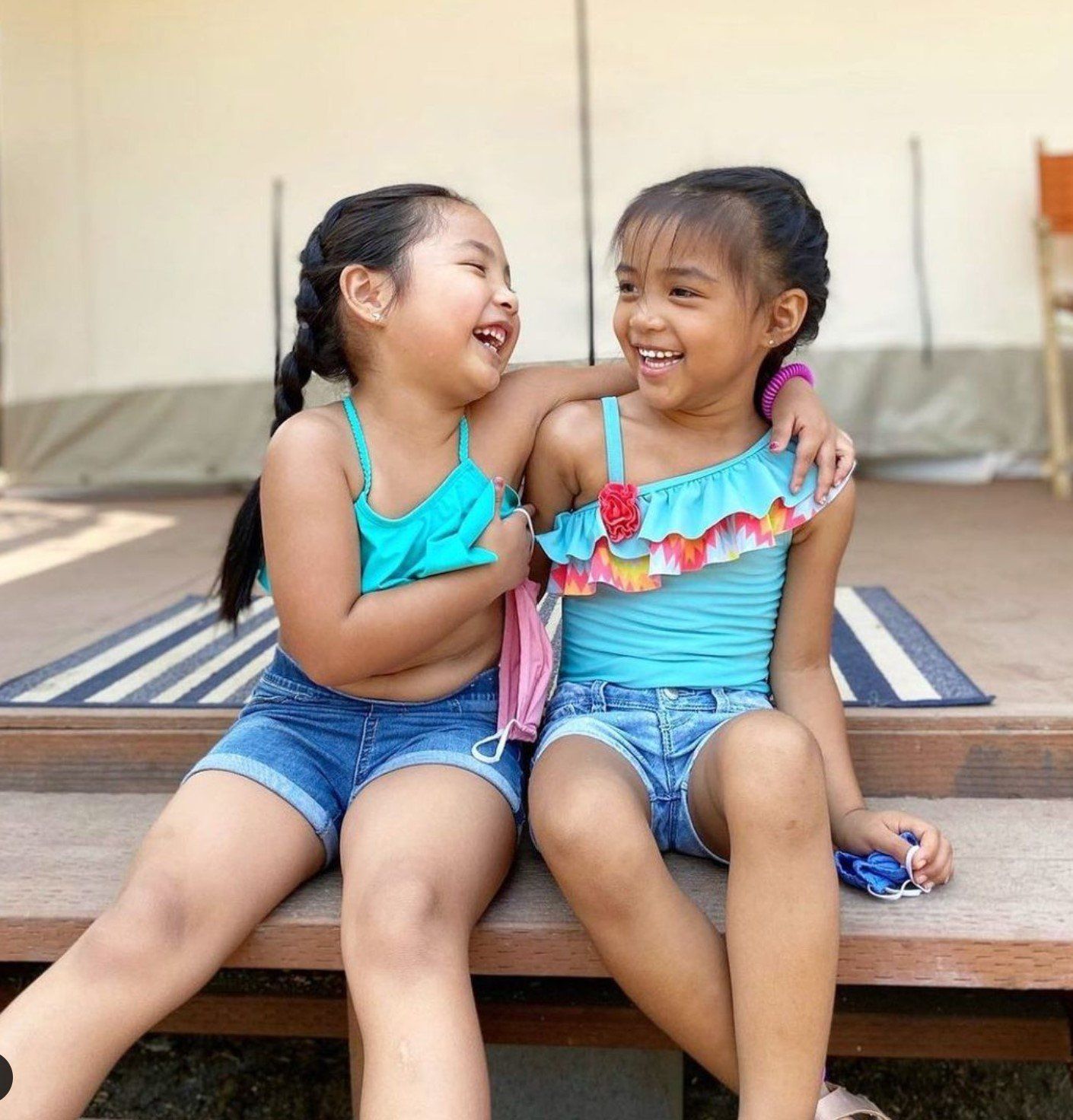 Two little girls are sitting on a bench and laughing