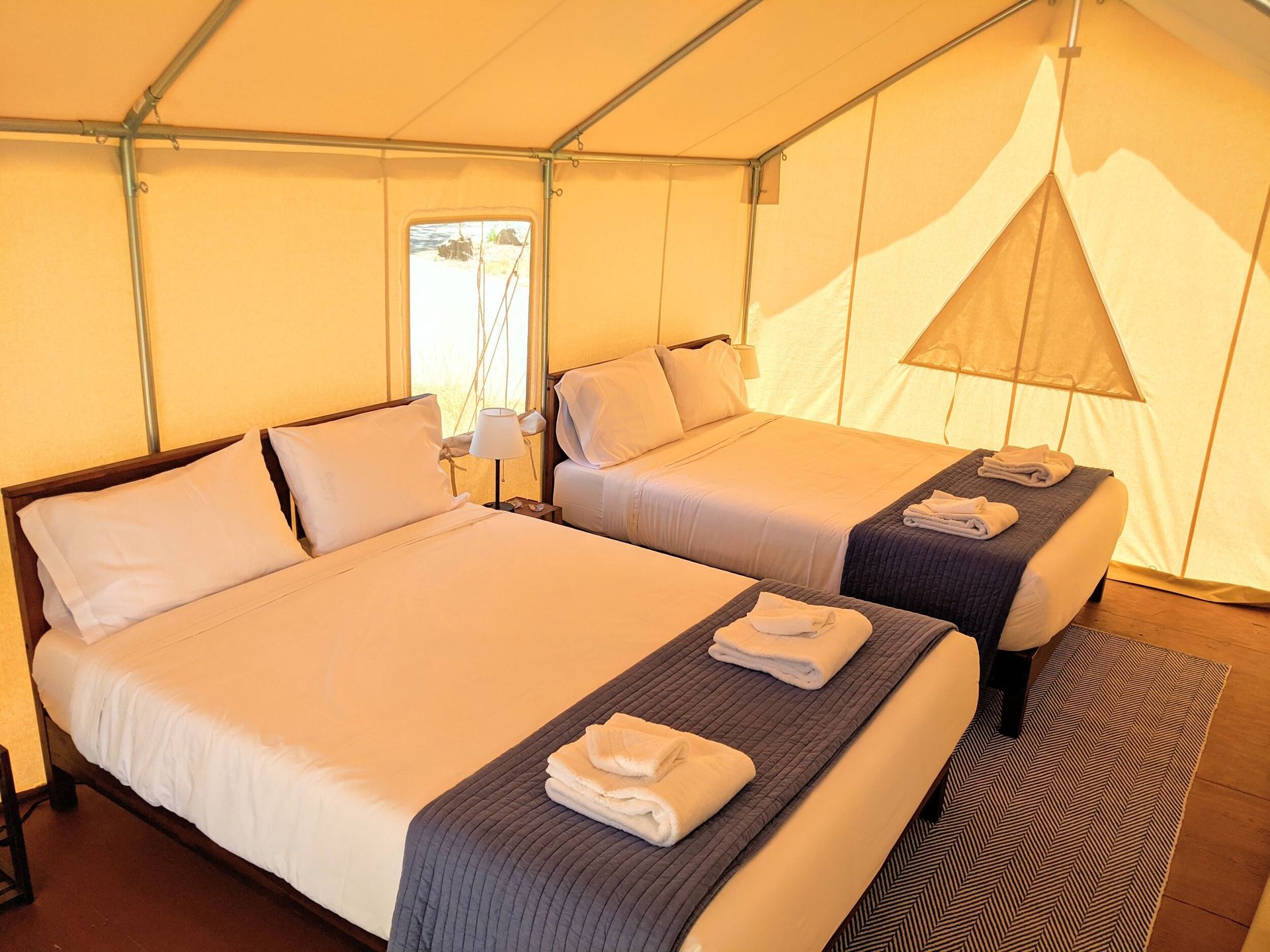 A tent with two beds and a rug in it