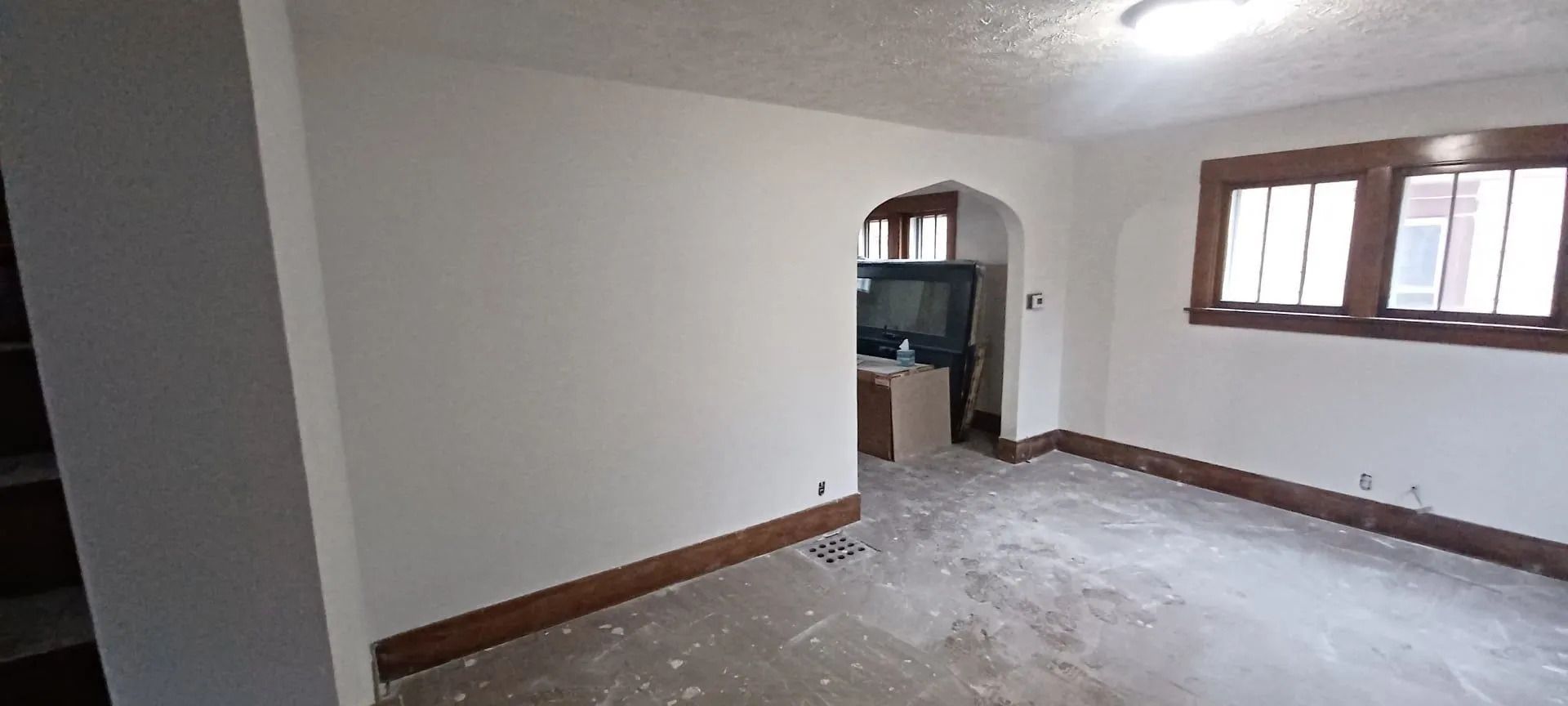 An empty living room with white walls and a concrete floor.