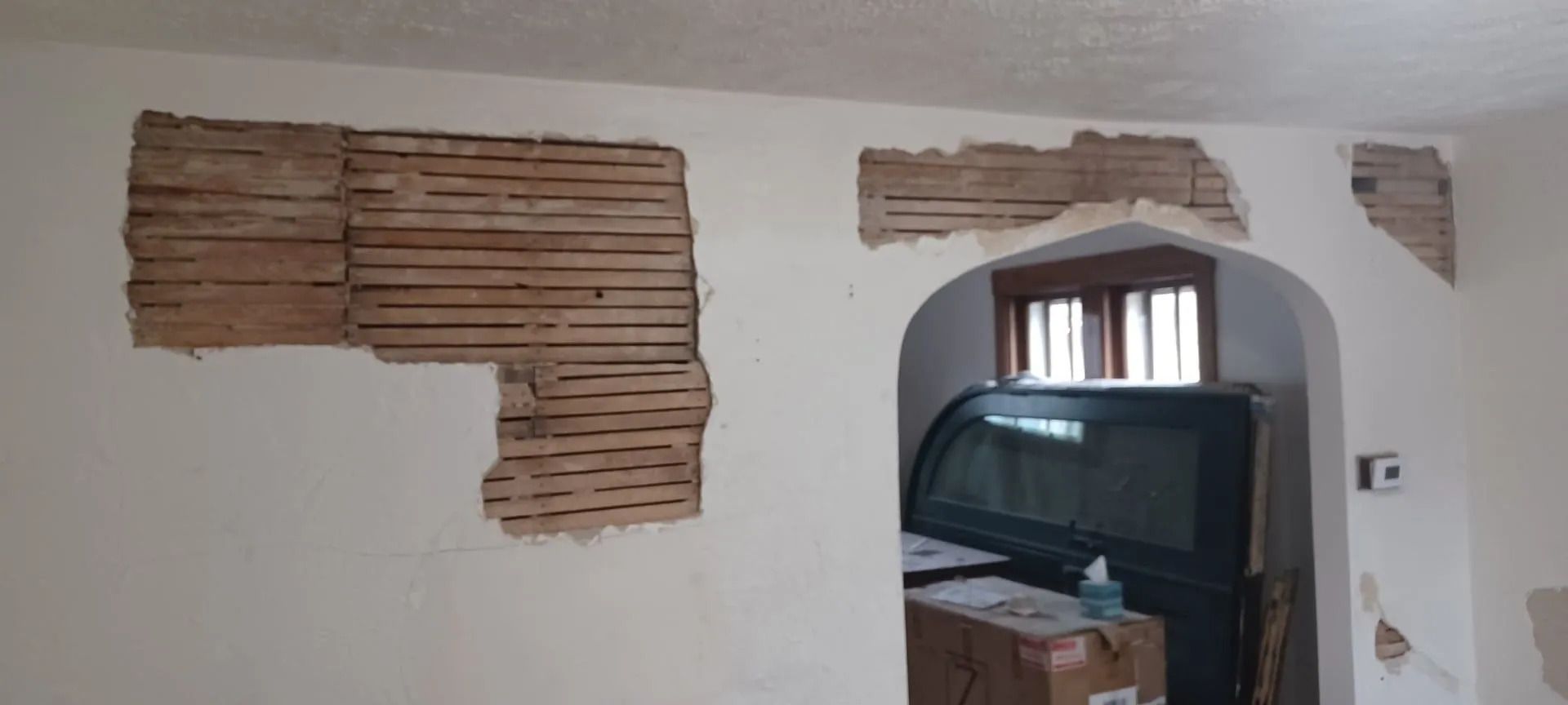 A room with a hole in the wall and a tv on the floor.