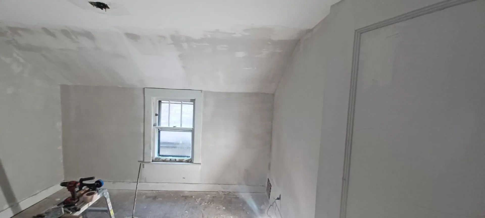 A room with a window and a ladder in it.