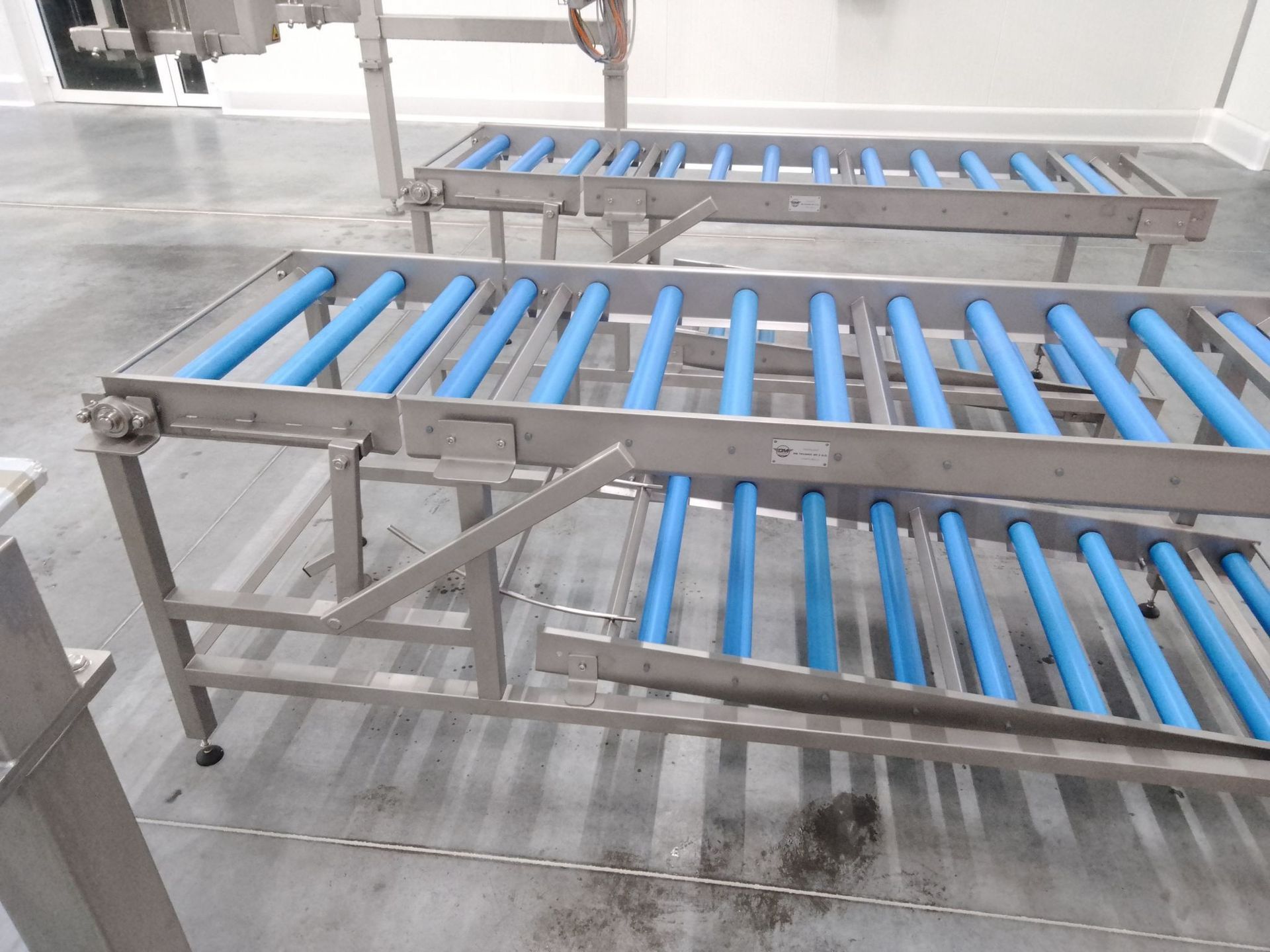 Stainless steel gravity roller conveyor with blue PVC rollers for efficient material handling – DM Technic.