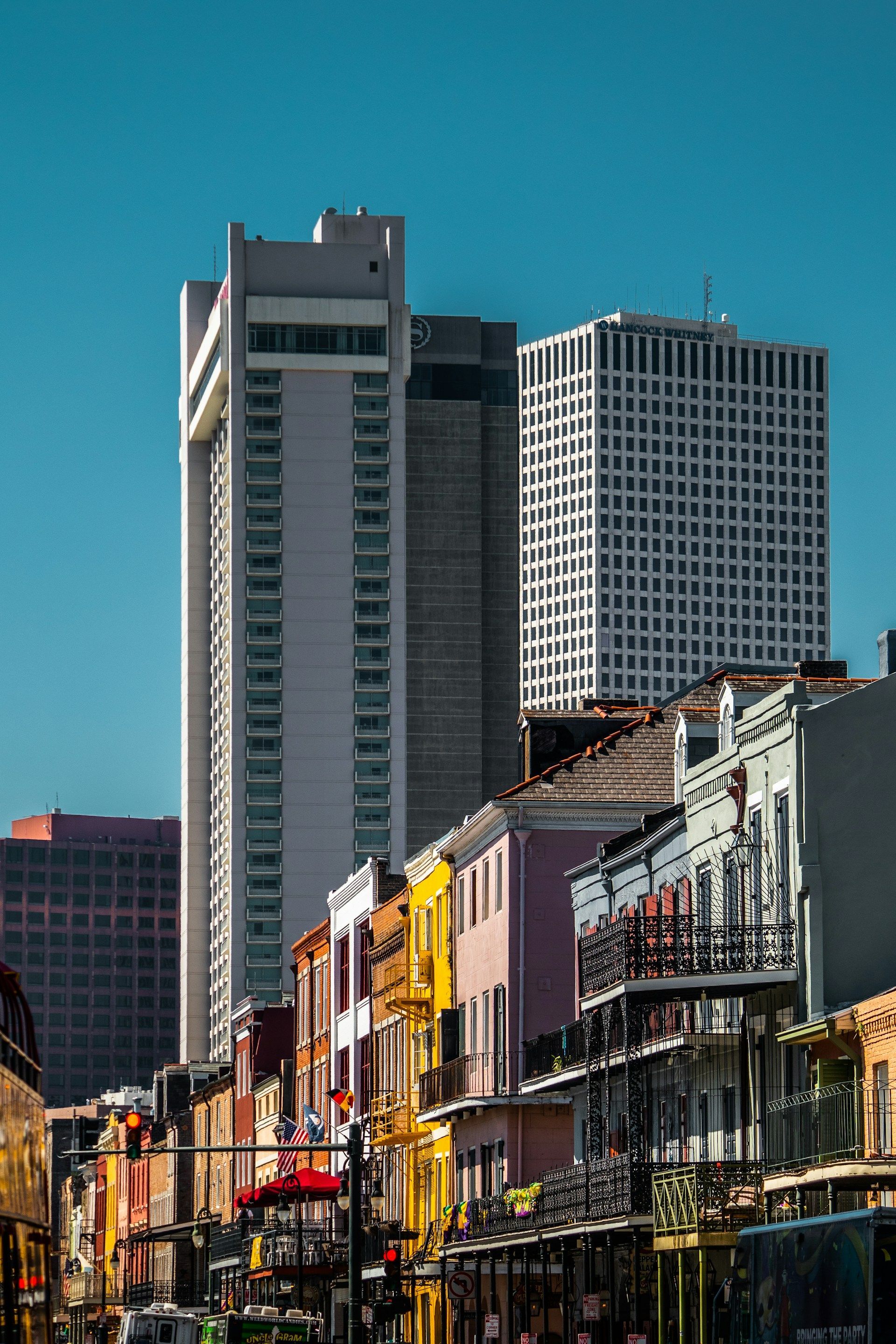 Colorful buildings line a street with skyscrapers in the background under a clear blue sky.
