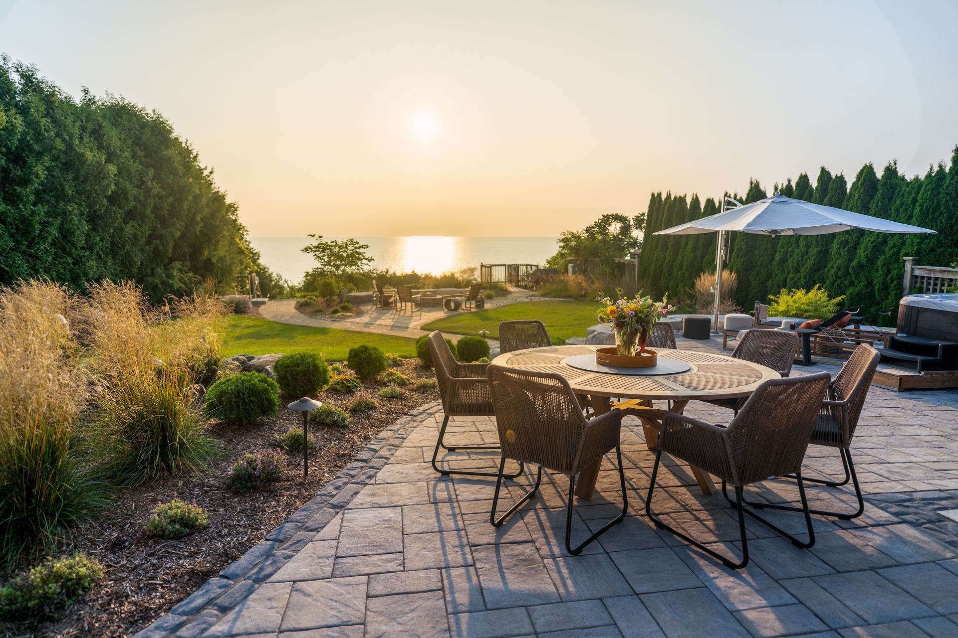 Patio with table and chairs overlooking a lake at sunset.