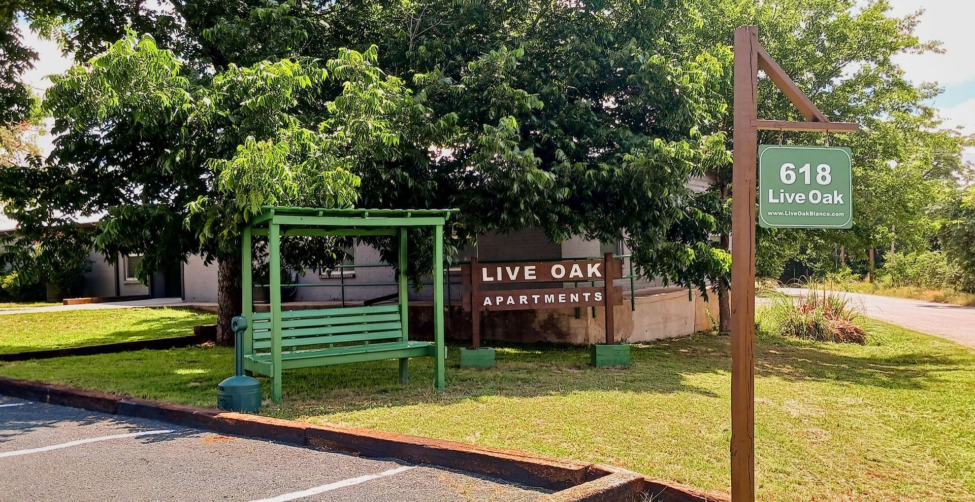 Green community sign for Live Oak, with trees and a wooden post marker reading 518