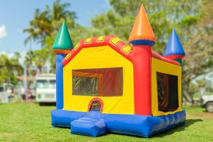 Colorful inflatable bounce house with red, yellow, blue, and green turrets on a grassy lawn