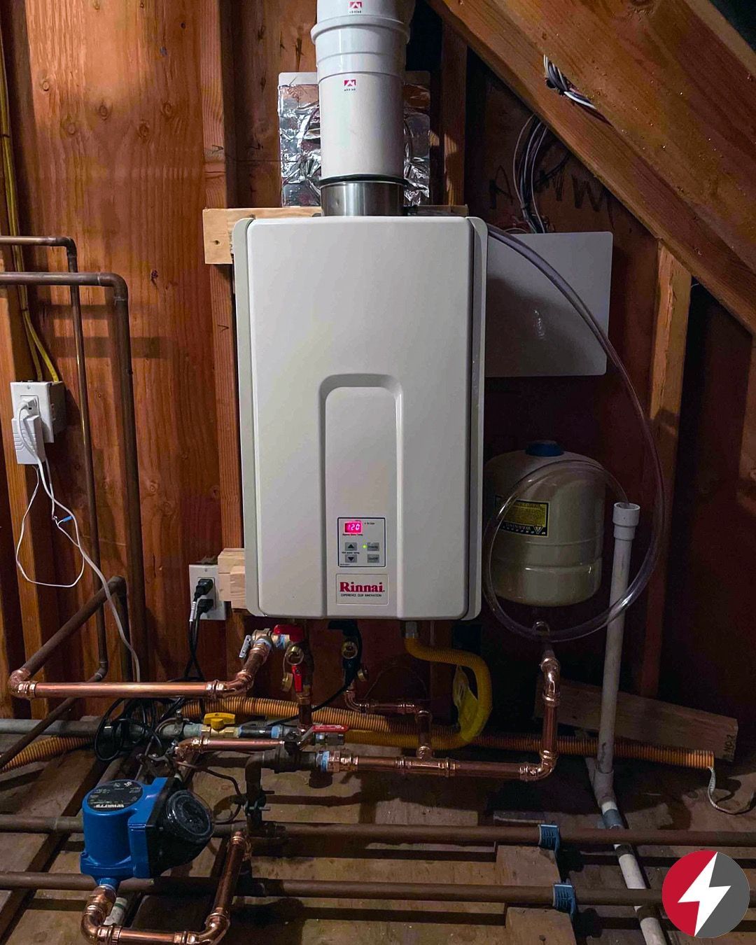 Tankless water heater installation with copper pipes in an attic.