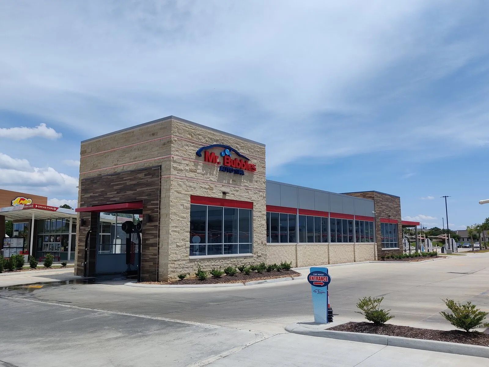 Exterior of a car wash building with a red and gray facade, under a blue sky.